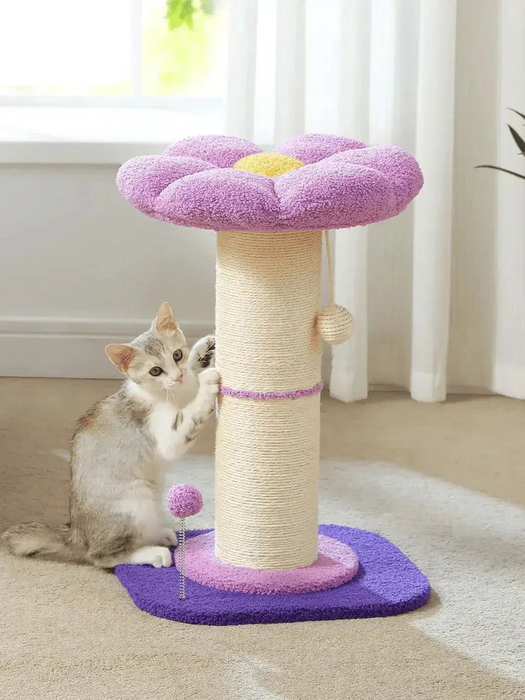 Griffoir fleur pour chat violet Floréa installé dans un salon avec un chat près du double poteau en sisal